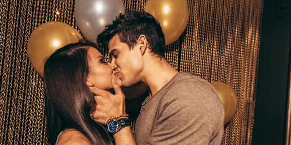 couple kissing with golden balloons in the background