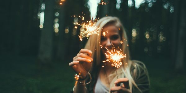 Blond girl holding sparkle candles on both hands